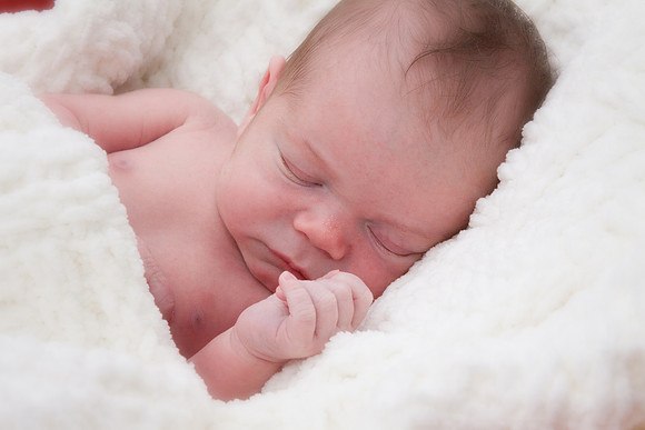 Newborn boy in cozy white blanket